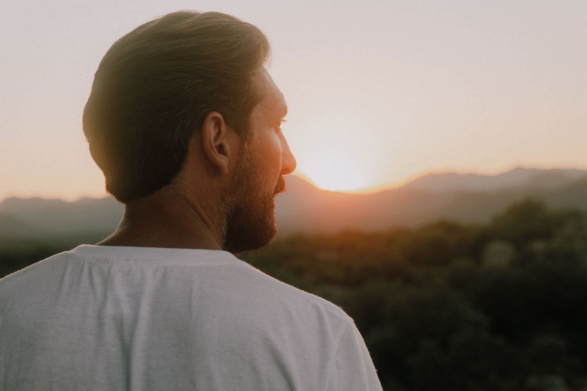 Un homme de dos au couch&eacute; du soleil porte un t-shirt ecru