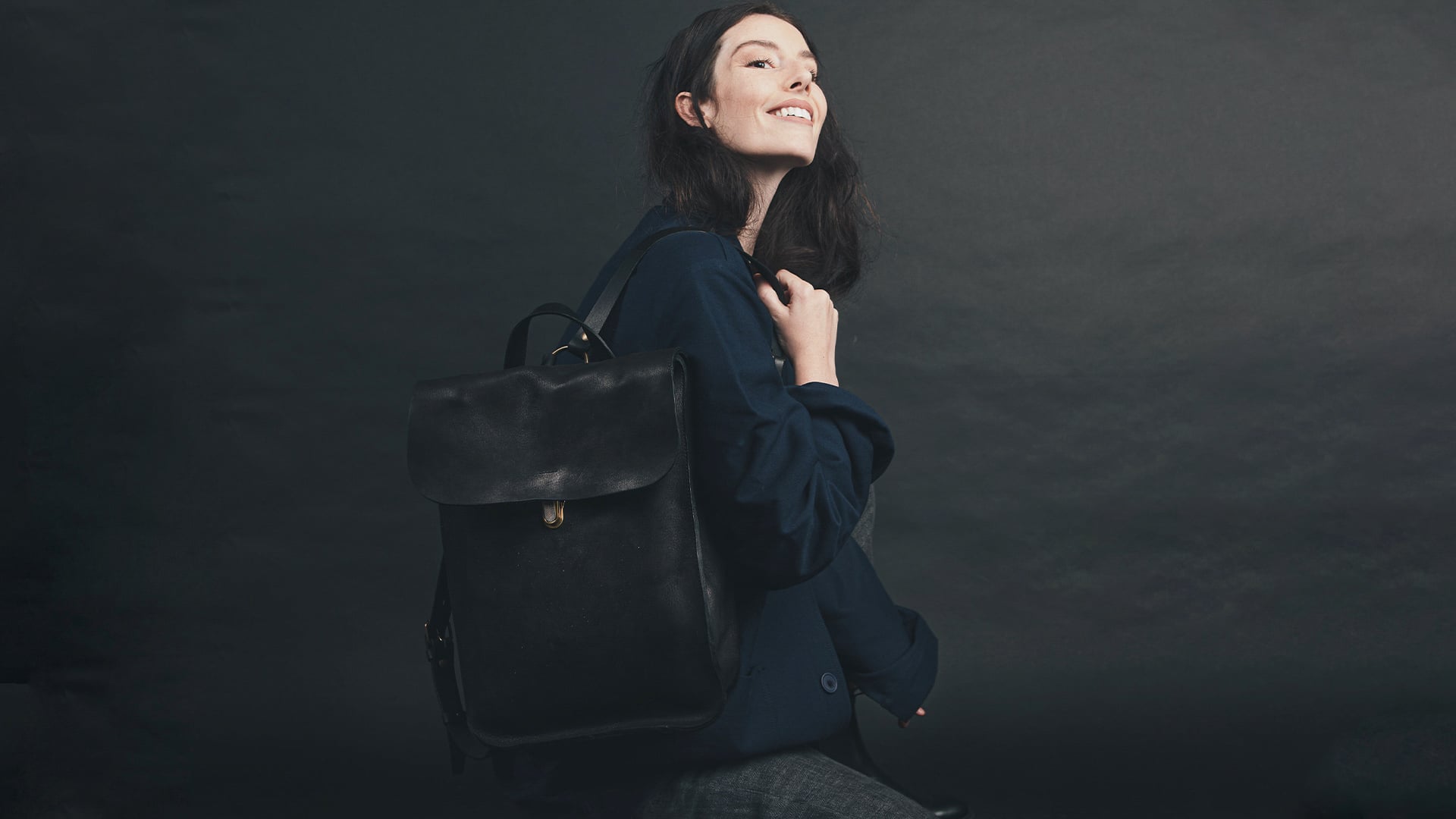 Une femme porte la veste de travail et un sac a dos en cuir